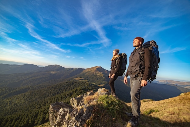 The happy couple standing on the sunny mountain