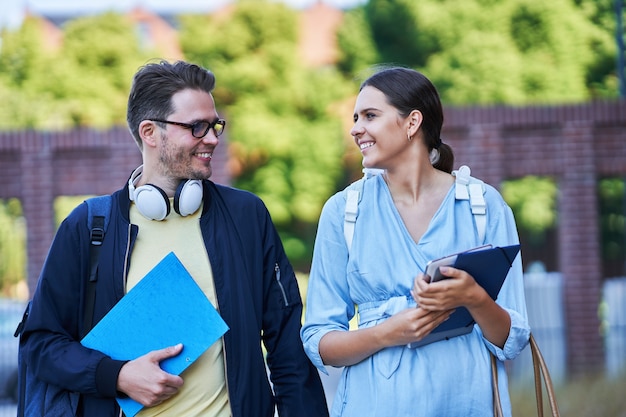 happy couple of students in the campus studying outdoors