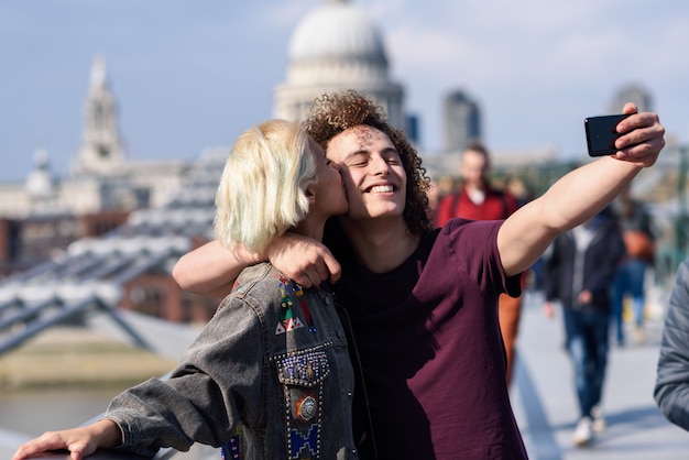 Happy couple taking a selfie photograph on London's Millennium Bridge