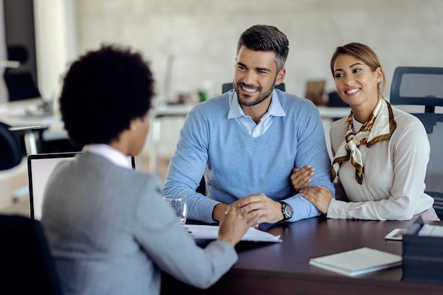 Happy couple talking about terms of agreement with insurance agent in the office