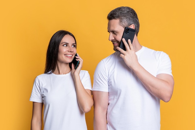 Happy couple talking on mobile phones couple making mobile call in studio