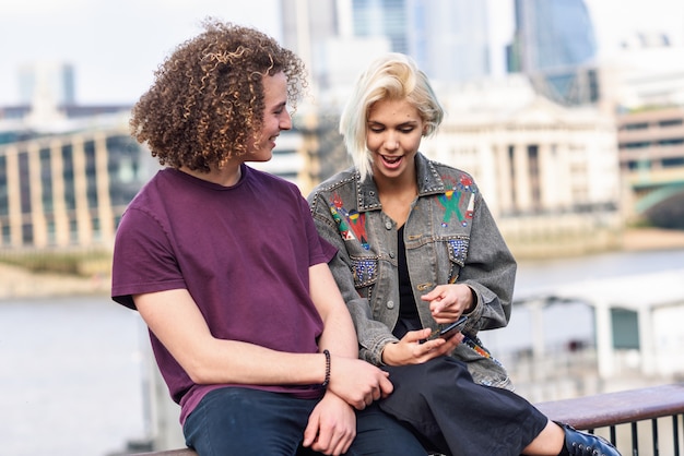 Happy couple talking sitting near River Thames.