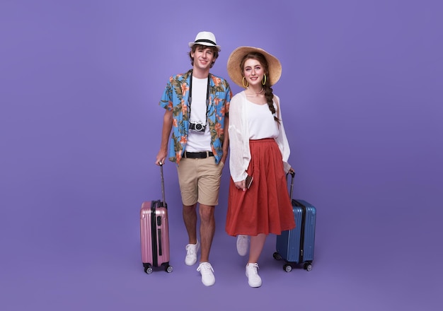 Happy couple tourist with baggage going to travel on holidays isolated on purple background