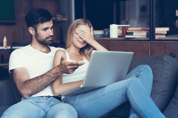 Happy couple using a laptop on the sofa