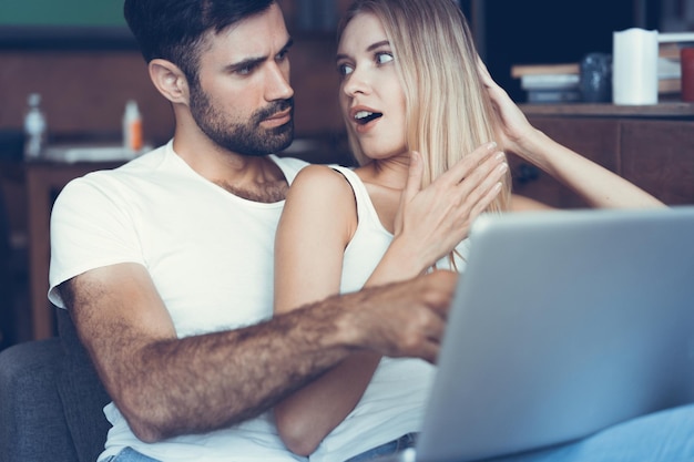 Happy couple using a laptop on the sofa