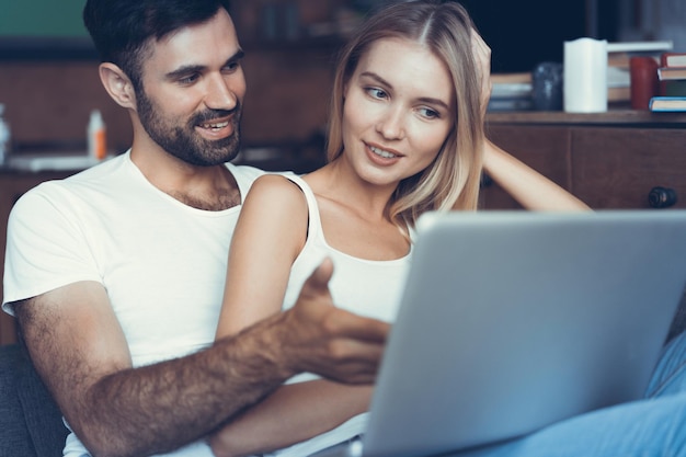 Happy couple using a laptop on the sofa