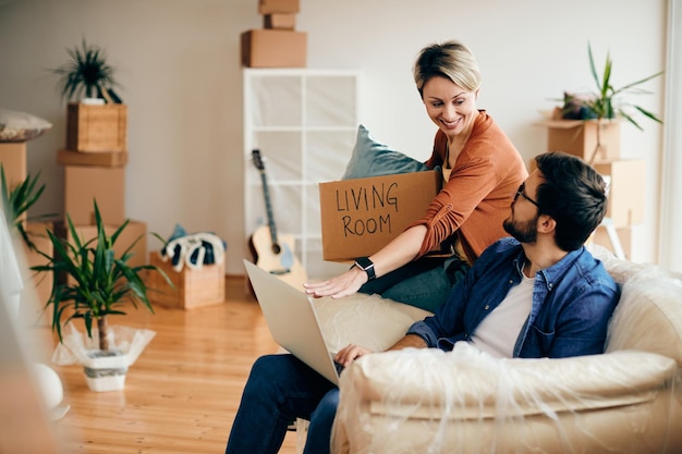 Happy couple using laptop while moving into new home