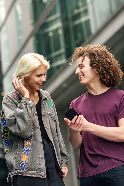 Photo happy couple using smartphone in urban background.