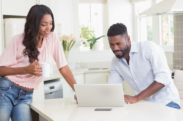 Happy couple using their laptop at breakfast