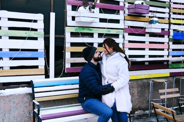 Happy couple walking in city. Young business man in a blue jacket, beard. cute woman in long coat.