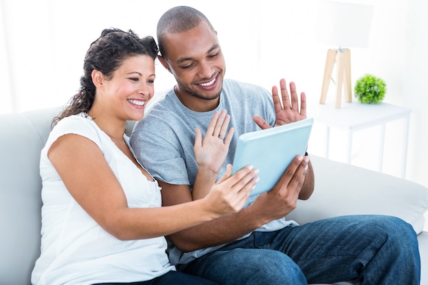 Happy couple waving at tablet