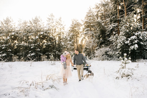 Happy couple on a winter day with retro car and husky