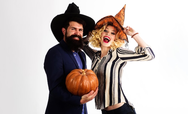 Happy couple in witches hats with jackolantern magic pumpkin preparation for halloween holidays