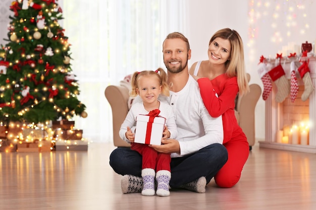 Happy couple with daughter and Christmas gift at home