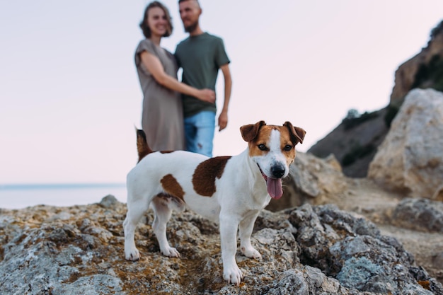 Happy couple with favourite pet Young man and woman have walk near sea