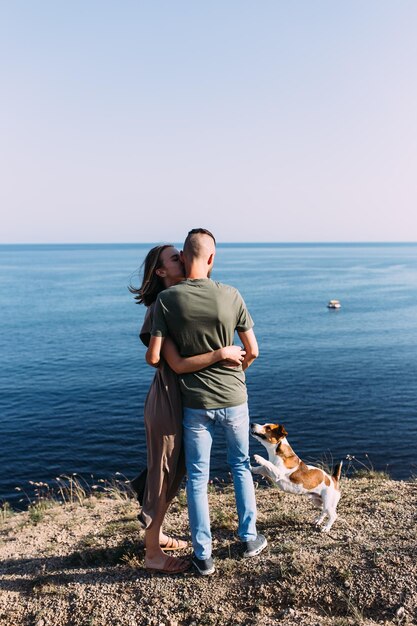 Happy couple with favourite pet Young man and woman have walk near sea