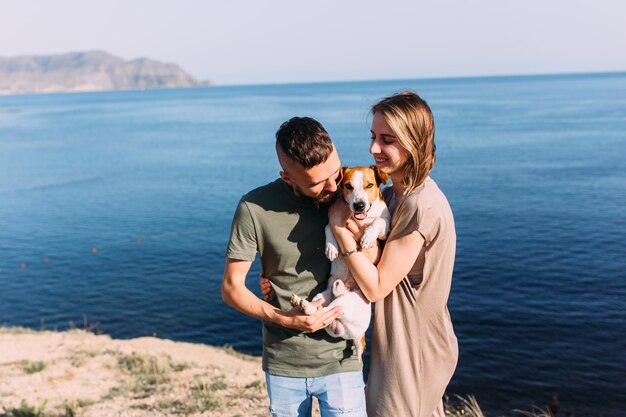 Happy couple with favourite pet Young man and woman have walk near sea