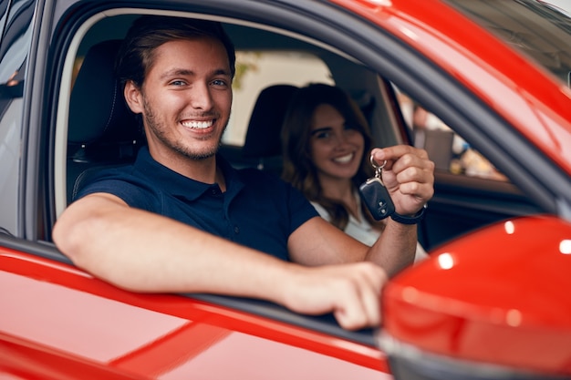 Happy couple with keys in car