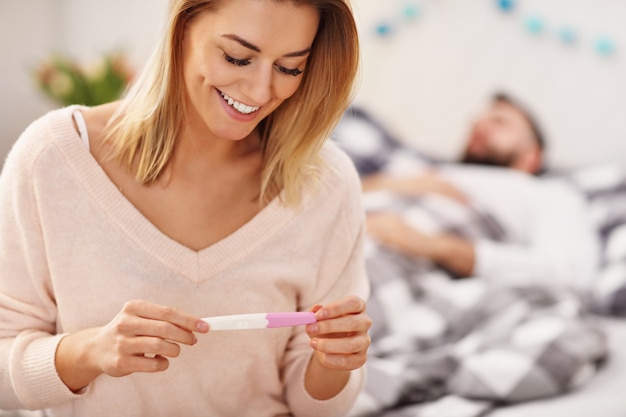 happy couple with pregnancy test in bedroom