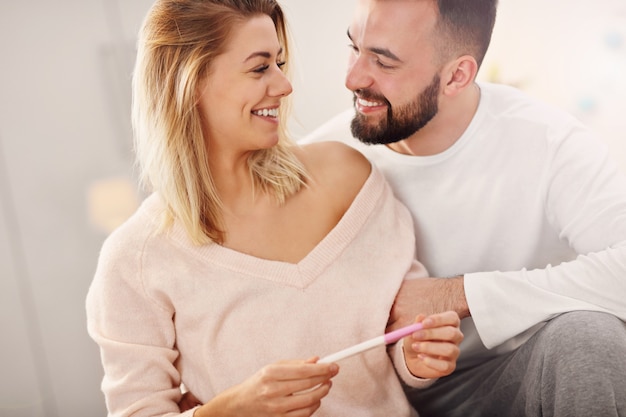 happy couple with pregnancy test in bedroom