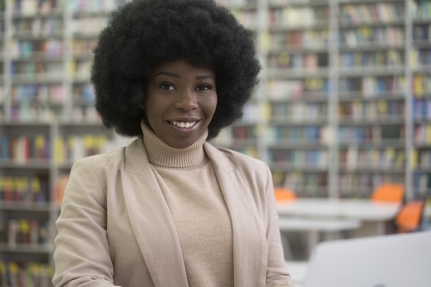 Happy curly haired Nigerian student studying sitting in library education concept