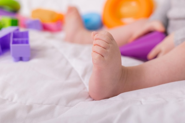 Happy cute baby girl 7 months old at home on the bed playing with educational toys Child development Comfort at home