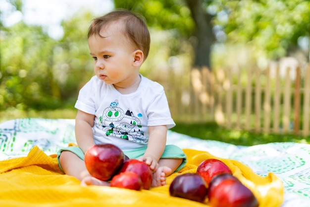 Happy cute child in the garden Cute little newborn baby sitting with apples