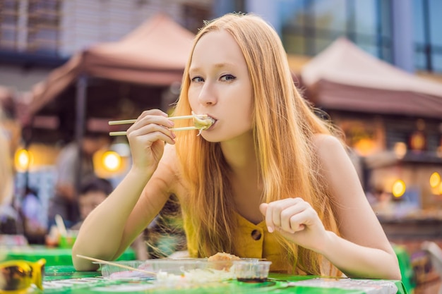 Happy cute gilr eating street food and looking enjoyable in a traditional small fair