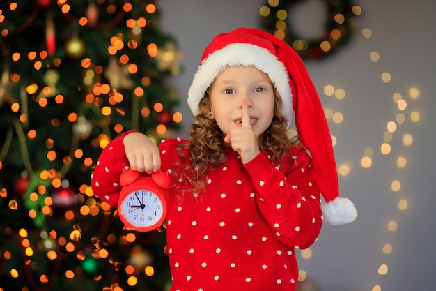 Happy cute girl waiting for the new year with an audio clock in her hands