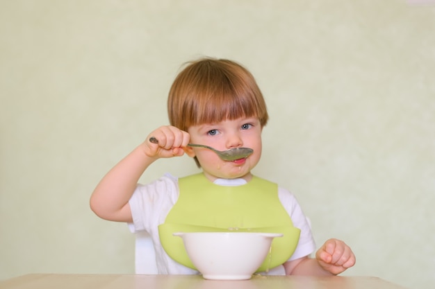 Happy cute infant baby boy spoon eats itself