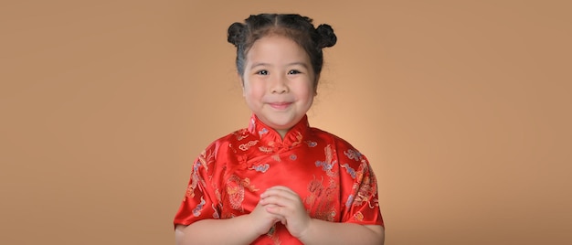 Happy cute little asian girl  wear a red chinese traditional cheongsam with copyspace for the celebration of the Chinese New Year.Happy chinese new year.