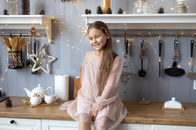 happy cute little girl in beautiful dress preparing tea christmas morning in the kitchen Christmas family harmony Christmas child in the kitchen