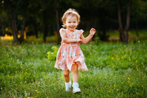 Happy cute little girl running on the grass in the park. Happiness.