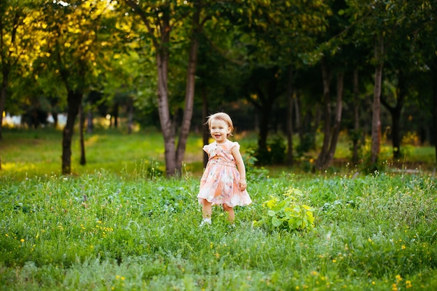 Happy cute little girl running on the grass in the park. Happiness