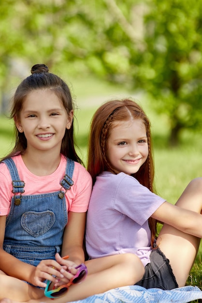 Happy cute little girls sitting together in the park. friendship and childhood