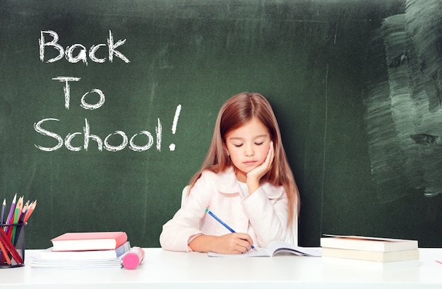 Happy and cute teen school girl writes in a book or notebook