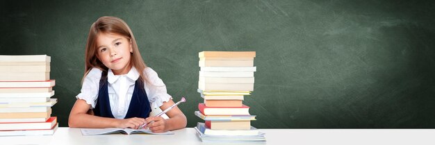 Happy and cute teen school girl writes in a book or notebook