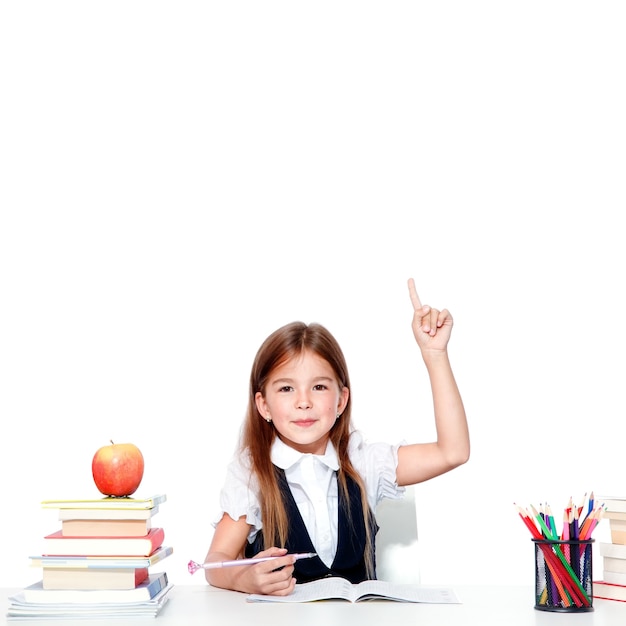 Happy and cute teen schoolgirl raising hand in classroom