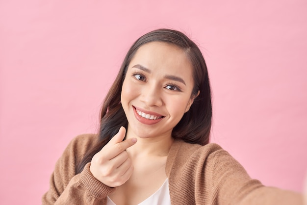 Happy cute woman making selfie over pink background