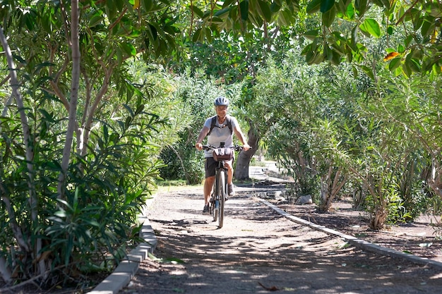 Happy cyclist woman riding in public park with electro bicycle and helmet Senior woman smiling enjoying healthy lifestyle and freedom