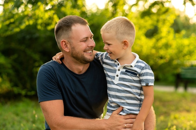 Happy dad happily hugs his son in the garden. father's day. concept of family happiness, fatherhood, outdoor play together.