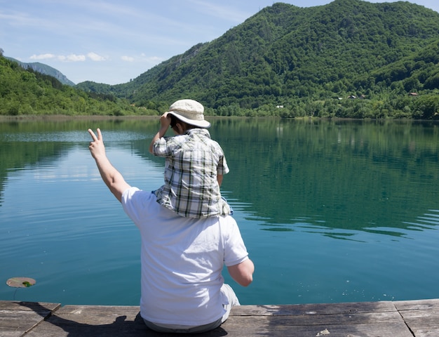 Happy dad and son on summer vacation having fun and happy time next to the mountain lake