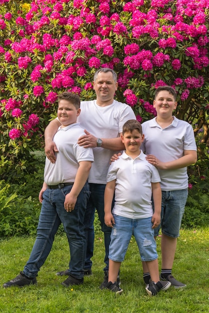 Happy dad and three sons joyfully hug each other Big family