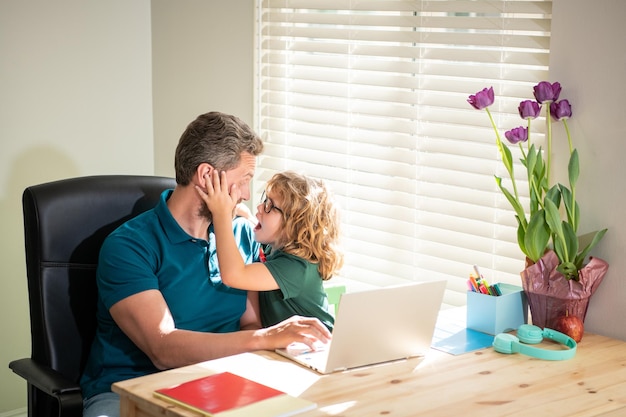 Happy daddy or teacher helping his school son kid in glasses study with pc in classroom parenthood