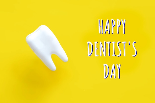 Happy Dentists Day greeting card and white tooth on yellow backgroundxA