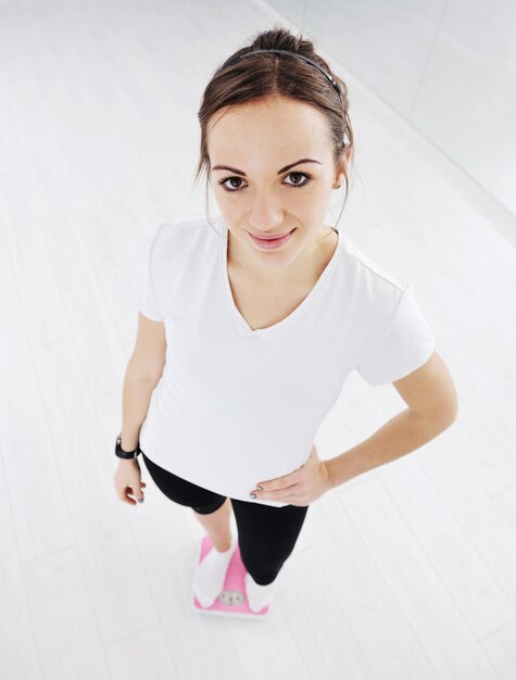 happy diet concept with young woman on pink scale at sport fitnes gym club