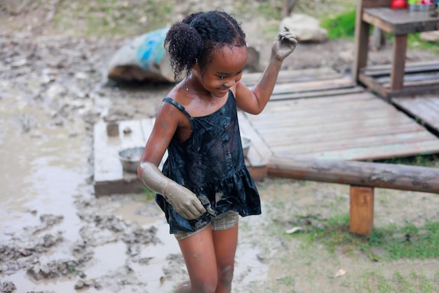 Happy dirty AHappy dirty African girl running in puddle mud at outdoor summer camp learning frican running in puddle mud at outdoor summer camp learning