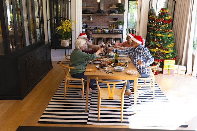 Photo happy diverse group of senior friends toasting at christmas dinner in sunny dining room at home