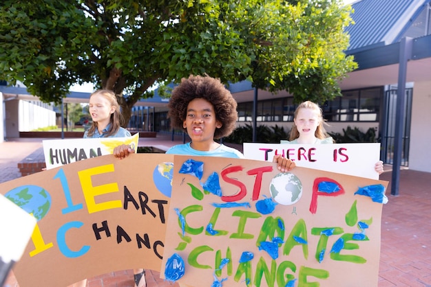 Photo happy diverse schoolchildren holding ecology posters made in art class outside school