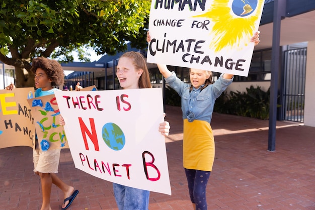 Photo happy diverse schoolchildren holding ecology posters made in art class outside school